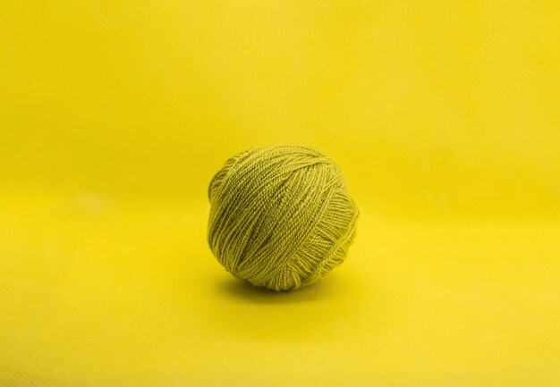 Photo boule de laine verte sur fond jaune vue frontale isolée