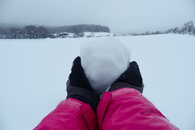 Boule de neige en mains sur fond d'hiver