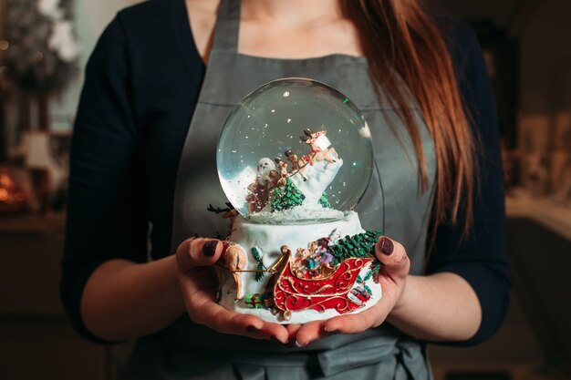 Boule de neige de Noël en verre en gros plan de mains féminines