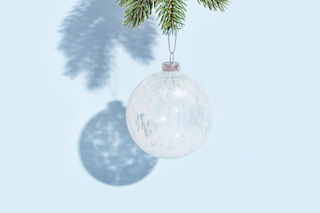 Boule de Noël accrochée à une branche de pin sur un mur de couleur bleue