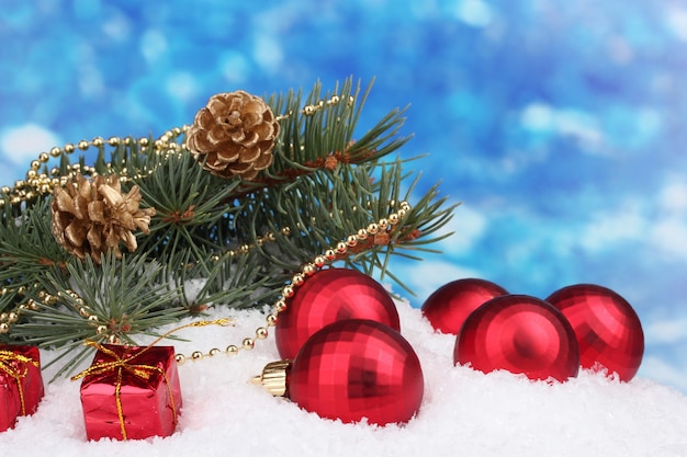 Boule de Noël et arbre vert dans la neige sur bleu