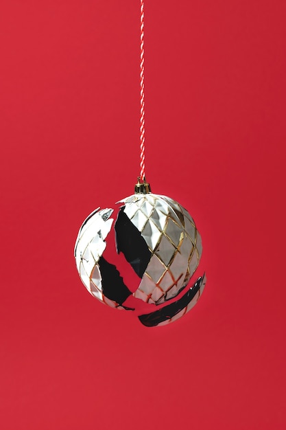 Boule de Noël blanche avec coquille brisée ou cassée suspendue sur fond rouge créatif minimaliste ...