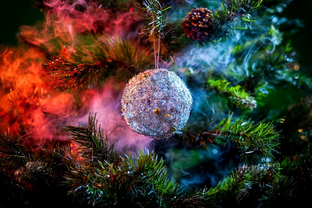 Boule de Noël brillante argentée de couleur violet et rouge fumée sur un arbre de Noël