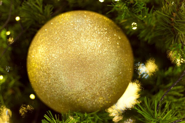 Boule de Noël dorée accrochée à la branche d'arbre