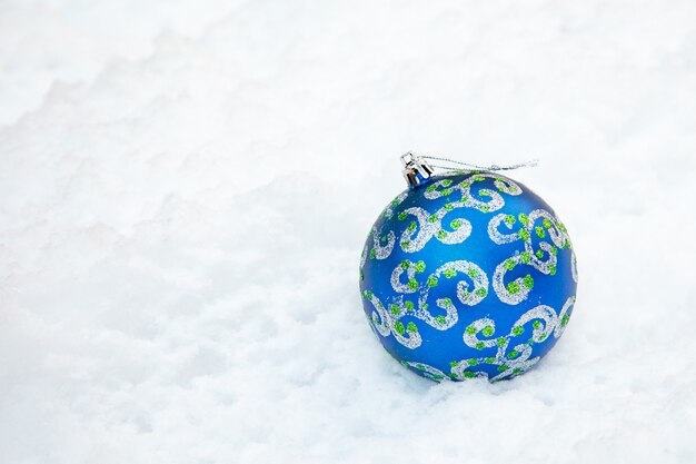 Boule de Noël sur fond bleu neigeux.