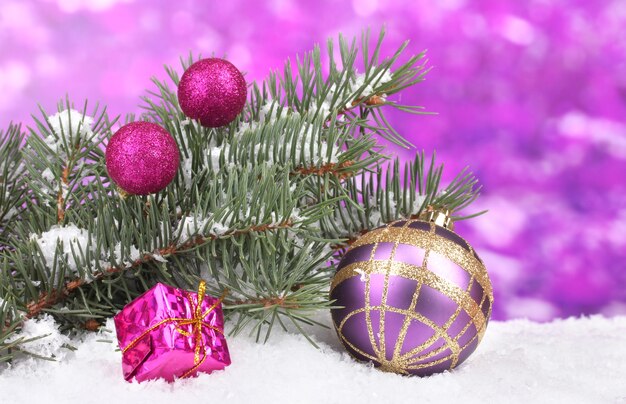 Boule de Noël et jouet avec arbre vert dans la neige sur mur violet