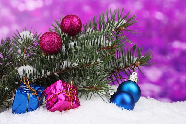 Boule de Noël et jouet avec arbre vert dans la neige sur violet