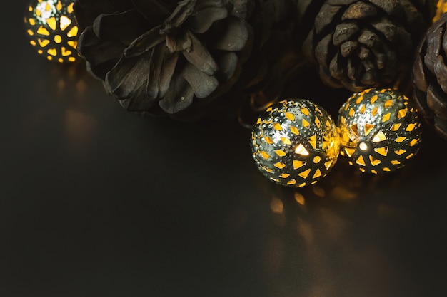 La boule de Noël et des pommes de pin sur fond noir.