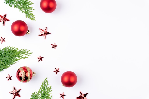 Boule de Noël rouge avec des branches d&#39;épinette verte et étoile sur fond blanc.