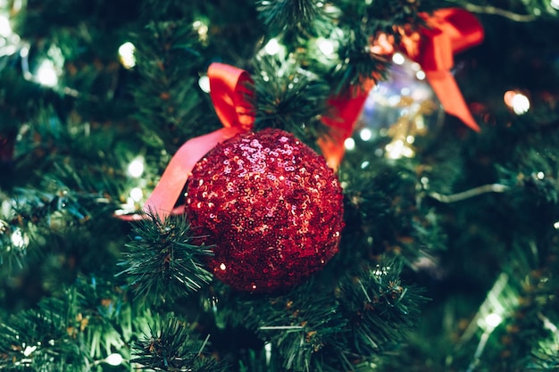 Boule de Noël rouge avec des étincelles sur un gros plan d'arbre de Noël