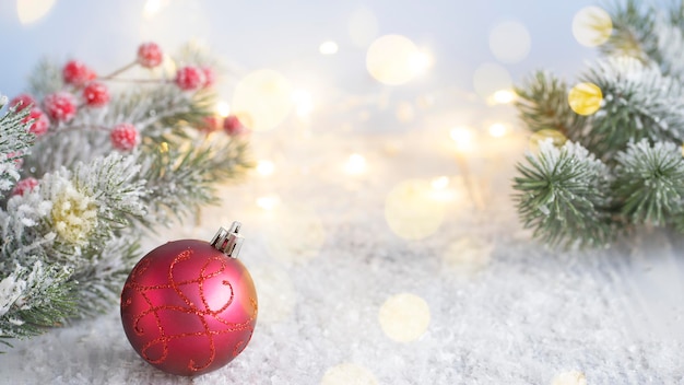 Boule de Noël rouge sur fond de branches de sapin