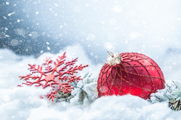 Boule de Noël rouge sur la neige avec des branches de sapin. Concept de joyeux Noël.