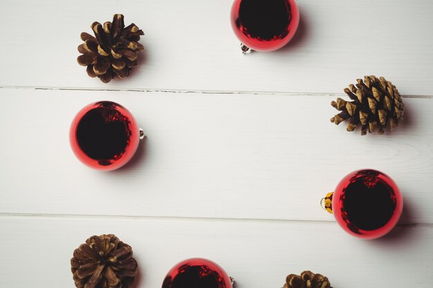 Boule de Noël rouge et pomme de pin sur table en bois