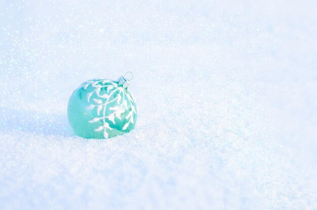 Boule de Noël en verre vert sur neige blanche