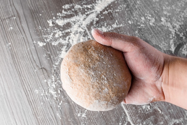 Boule de pâte de blé avec de la farine dans les mains