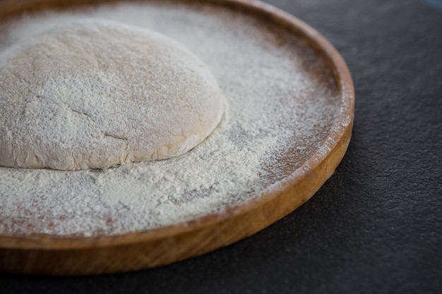 Boule de pâte à pizza sur un plateau en bois