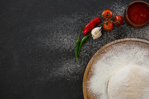 Boule de pâte à pizza sur un plateau en bois