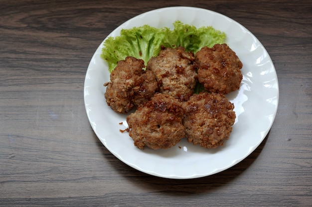 Boule de porc au poivre à l'ail frit dans une assiette blanche sur fond de bois.