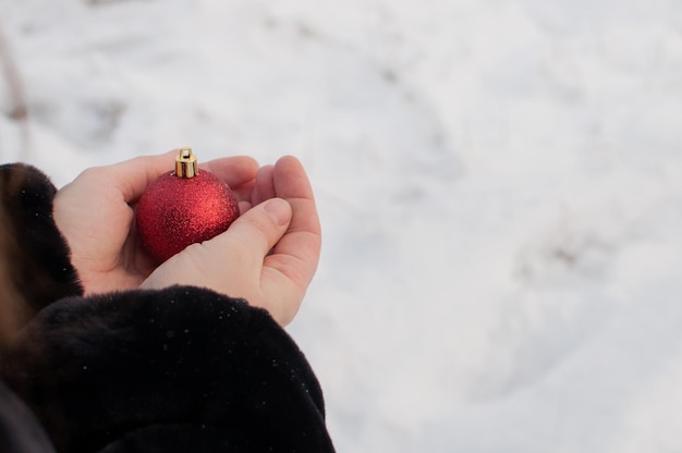 Une boule rouge brillante dans les mains des femmes sur un arrière-plan flou d'hiver