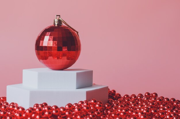 Boule rouge jouet arbre de Noël, sur un podium blanc