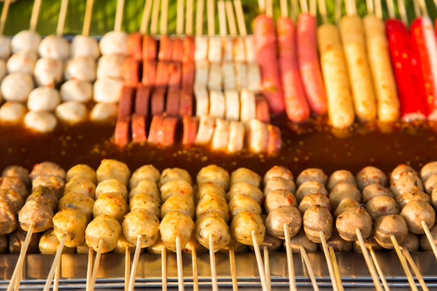 boule de viande et hot-dog avec un bâton de bois avec suace épicé sur la nourriture de rue