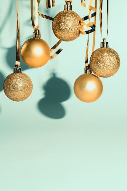 Boules et banderoles dorées de décoration d'arbre de Noël sur fond bleu avec espace de copie pour les salutations ou la publicité.
