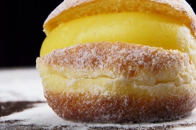 Boules de Berlin, connues sous le nom de Sonho au Brésil sur une table en bois avec du sucre glace éparpillé. Il se compose d'une pâte sucrée frite remplie d'une crème et de sucre sur le dessus. Mise au point sélective.