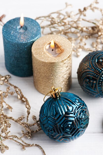 Boules bleues, bougies aromatiques dorées et jouets de Noël sur bois rustique