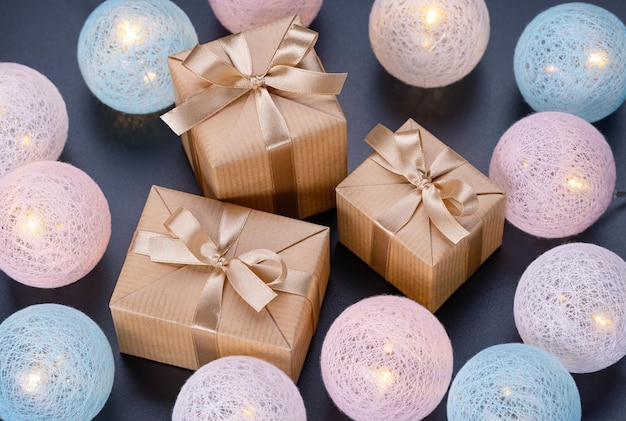 Boules et boîtes lumineuses avec des cadeaux en papier kraft avec des rubans et des arcs Noël et nouvel an holi