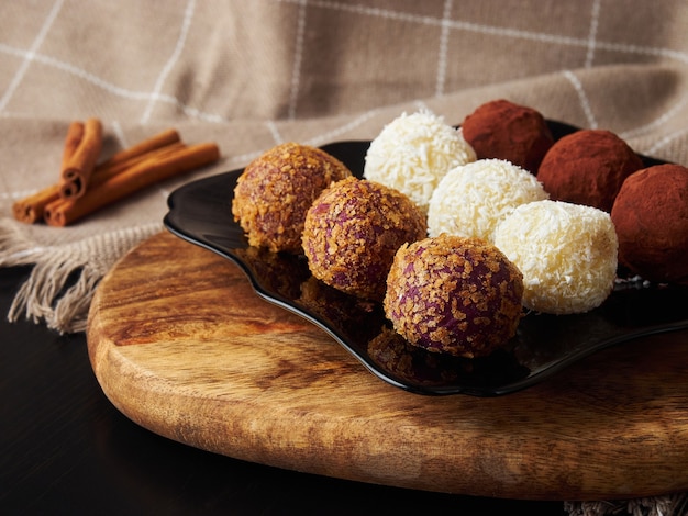 Boules de bonbons de Noël à la main sur une plaque noire et des bâtons de cannelle