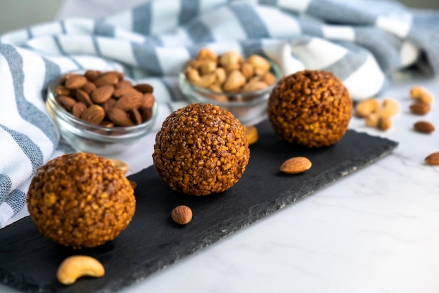 Boules de bonheur de dessert crues saines de noix de cajou et d'amandes sur planche de roche noire