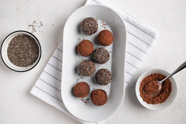 Boules de bonheur énergétique végétalien avec des dattes, des graines de chia et du cacao sur un plateau blanc, un dessert végétalien cru