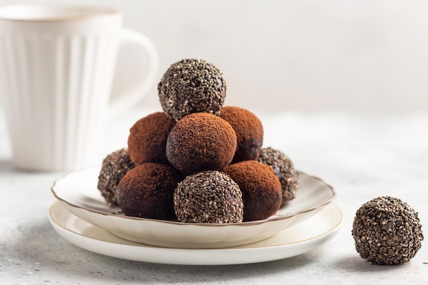 Boules de bonheur énergétique végétalien avec de la poudre de cacao aux graines de chia et une tasse de boisson chaude