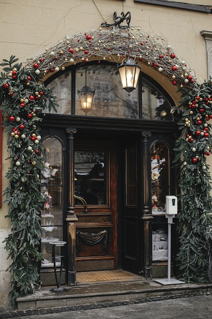 Boules et branches de Noël rouge et or élégantes sur la vieille porte avec lanterne Décor de Noël moderne dans la rue de la ville Vacances d'hiver en Europe Joyeux Noël et bonnes fêtes