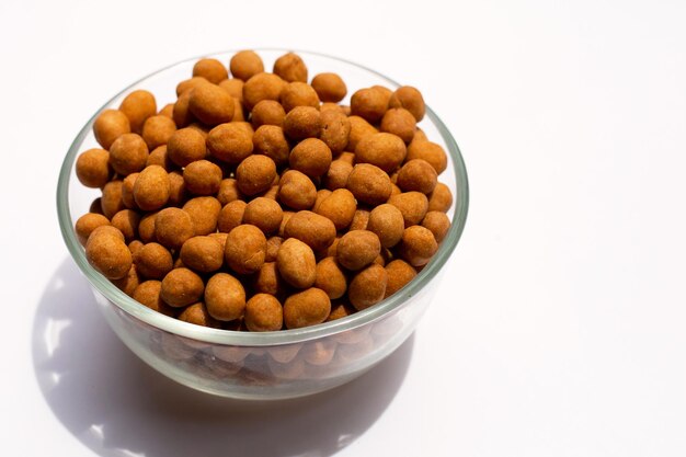 Boules de collation croustillantes aux arachides dans un bol en verre sur fond blanc.