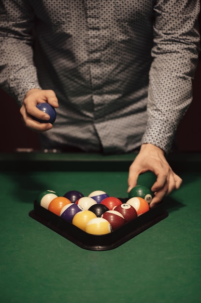 Boules de couleur de billard américain en triangle sur table de billard et joueur de billard close-up