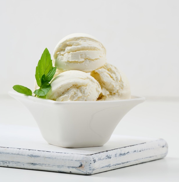 Boules de crème glacée à la vanille avec feuille de menthe verte dans une assiette en céramique blanche