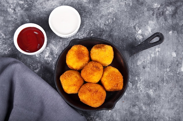 Boules de croquettes de pommes de terre sur la poêle en fer et tremper les sauces.