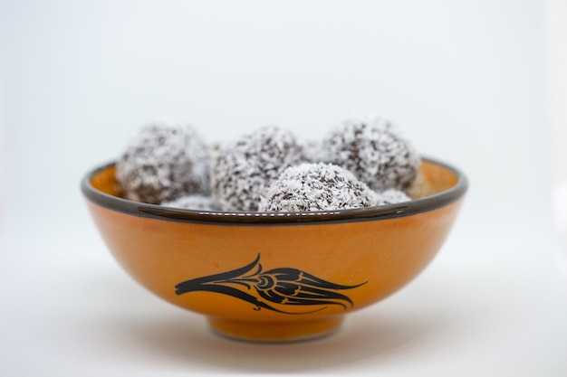 Photo des boules de dessert à la noix de coco devant un fond blanc dans un bol