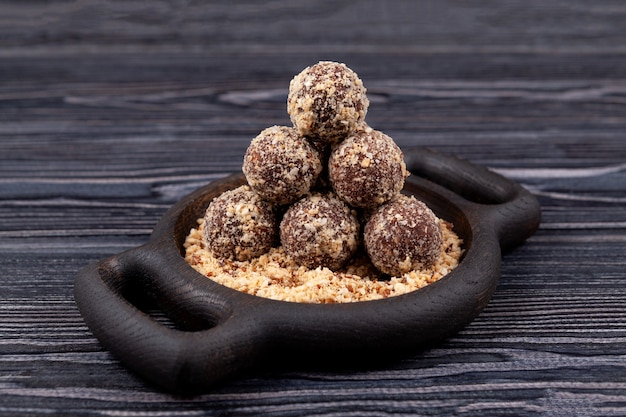 Boules d'énergie ou bonbons de fruits secs et noix sur plaque de bois