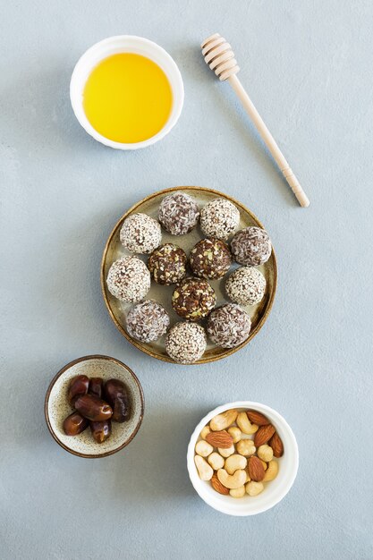 Boules d'énergie de bonbons sucrés avec des noix et des fruits secs sur la plaque à plat poser sur fond gris