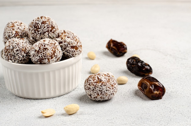 Boules d'énergie dans une assiette blanche et dates d'ingrédients, arachides pour leur préparation, mise à plat