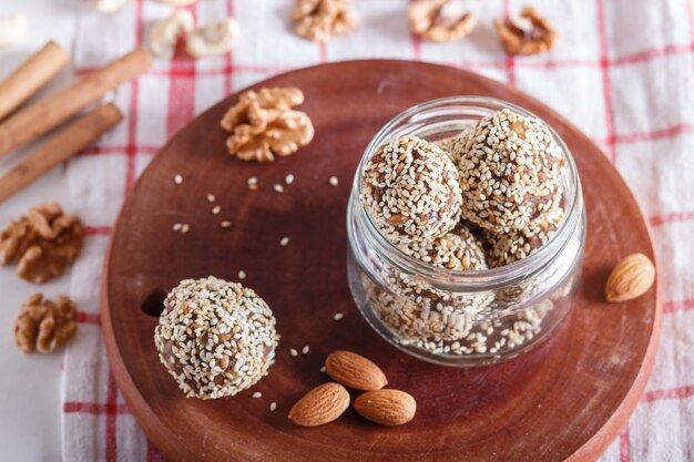 Boules d&#39;énergie gâteaux aux amandes, sésame, noix de cajou, noix, dattes et blé germé dans un bocal en verre, vue latérale, gros plan.