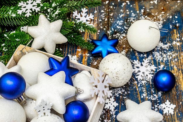 Boules et étoiles de Noël blanches et bleues, branches de sapin et flocons de neige. fermer