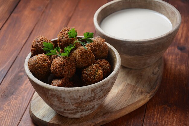 Boules de falafel au persil dans un bol en bois et sauce tahini