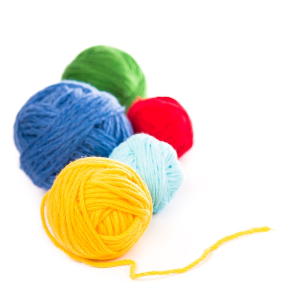 Boules de fils de laine bleus, rouges et jaunes sur fond blanc