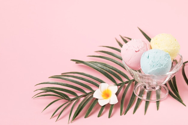 Photo boules de glace sur un bol en verre près du feuillage et des fleurs