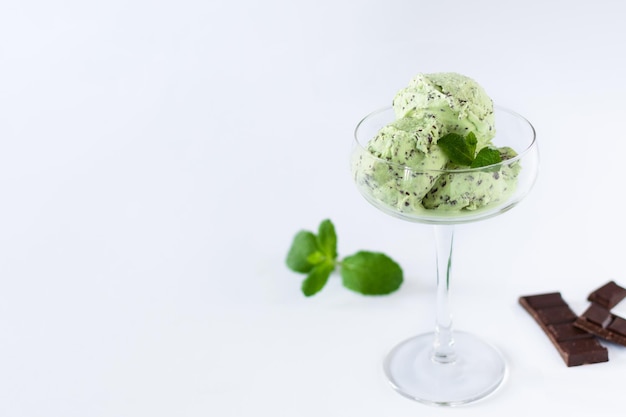 Boules de glace à la menthe avec miettes de chocolat dans un verre sur fond blanc