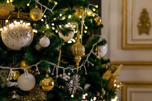 Boules et guirlandes de jouets de Noël d'or et d'argent sur une branche d'épinette sur l'arbre de Noël