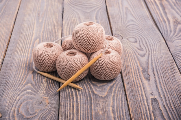 Boules de laine et des aiguilles à tricoter pour tricoter sur un fond en bois.